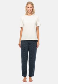 T-shirt basique crème clair à manches courtes associ�é à un pantalon de pyjama à pois navy dans une coupe décontractée. Le modèle est pieds nus.