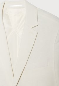 Beige Blazer mit Reverskragen, einer einzelnen Brusttasche und einem glatten Innenfutter. Der Stoff hat eine dezente Textur und einen raffinierten Finish.