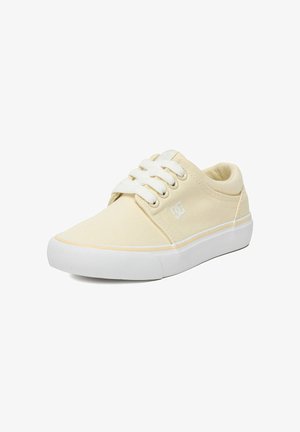 Beige lage canvas sneaker met witte veters, witte rubberen zool en klein DC-logo aan de zijkant.