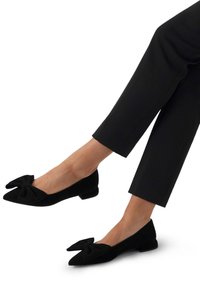Zwarte suède ballerina's met een spitse neus en een strikaccent aan de voorkant. G gedragen met cropped zwarte broeken, met een ontwerp van een lage hak.
