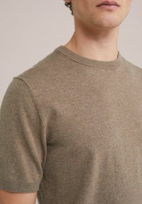 Brown short-sleeve knit sweater with a round neckline, crafted from a soft fabric. Features a subtle texture and ribbed edges.