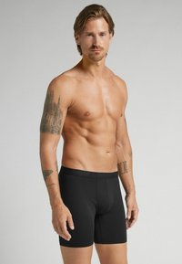 Boxer ajustados negros hechos de una tela suave y elástica. Presentan un ajuste ceñido con una parte frontal sin costuras y una cinturilla suave y elástica.