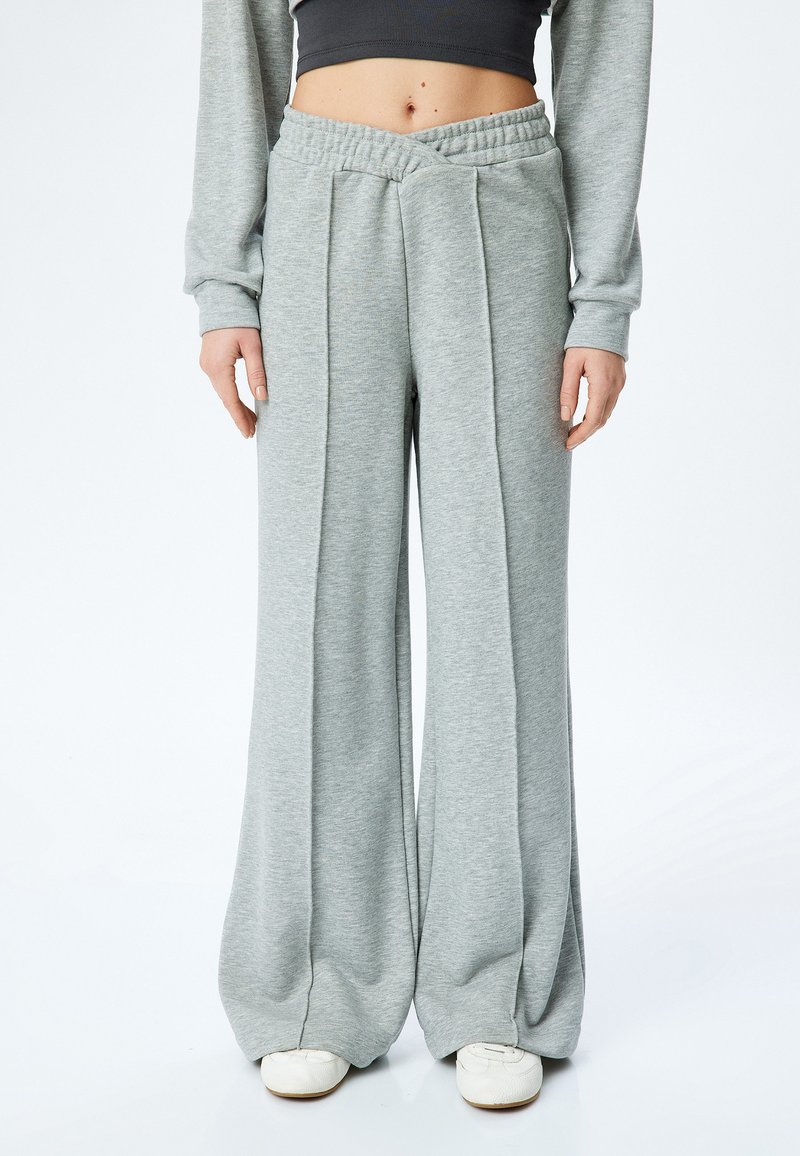 Hellegraue, weit geschnittene Sweatpants aus weichem Stoff. Sie verfügen über einen texturierten Bund mit Falten an der Vorderseite und eine entspannte Silhouette.