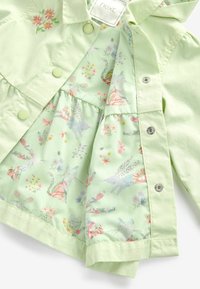 Lys grønne børnejakke med trykknapper, broderede blomster og indvendig foring mønstret med katte, kaniner, frøer og sommerfugle.