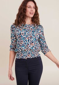 Top a fantasia con maniche a tre quarti nei toni del blu, bianco e arancio. Presenta una vita arricciata, tessuto testurizzato e scollatura rotonda.