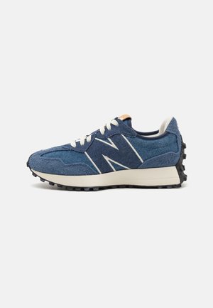 Zapatillas de gamuza azul con un logo blanco, cordones color crema, suela de goma duradera y detalles de tela texturizada, diseñadas para ofrecer comodidad y estilo.