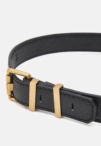 Mustavartaloinen nahkavyö, jossa on kultasävyistä metallia, neliömäinen solki ja palkkiakselit, suunniteltu turvalliseksi kiinnittämiseksi.