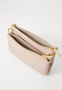 Beige leather pouch with two zippered compartments, gold-tone hardware, and textured exterior. Smooth lining visible inside compartments.