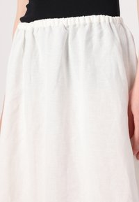 Weißer Leinenrock mit einem elastischen Bund, der eine weiche, leichte Textur und ein luftiges Design aufweist.