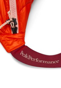 Heldere oranje pufferjas met een gestructureerd oppervlak, voorzien van een roze rits en een rode stoffen band met "PeakPerformance" in witte letters.