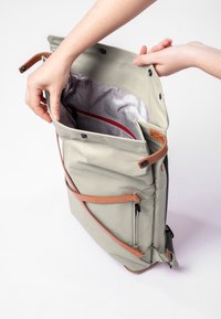 Zaino in tessuto grigio con dettagli in pelle, dotato di chiusura a pattina, più tasche e fodera interna a motivo.