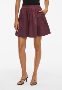 Jupe A-line bordeaux en tissu doux, dotée d'une taille haute et de deux poches latérales pour plus de fonctionnalité.