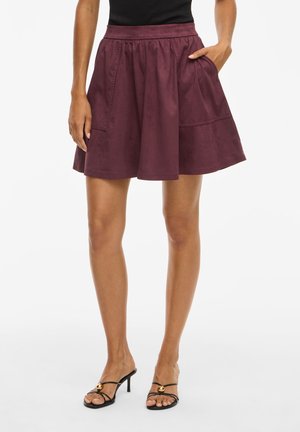 Burgundy A-line skirt made of soft fabric, featuring a high waistband and two side pockets for functionality.