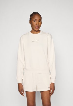 Lichtcrème sweatshirt met een ronde hals, geribbelde manchetten en zoom, met een grijs logo in het midden. Gecombineerd met bijpassende shorts.