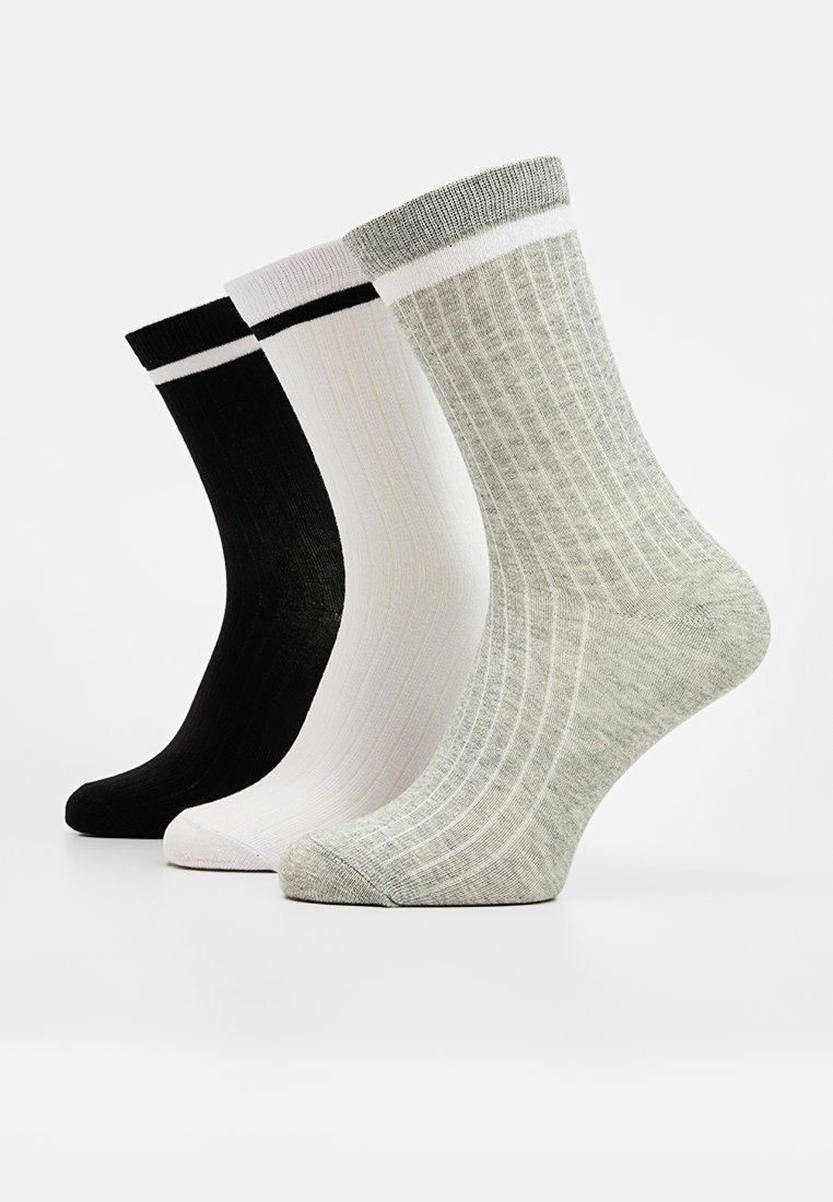 Tres pares de calcetines de tripulación: negros con rayas blancas, blancos con rayas rosas y grises con textura acanalada, todos con un diseño de color sólido.