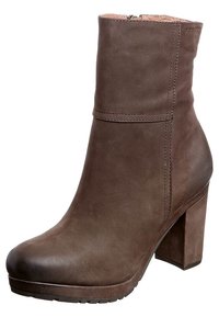 Botte de cheville en cuir marron avec un talon épais, texture lisse, bout arrondi et fermeture éclair sur le côté. Les détails de couture ajoutent une touche de design subtile.