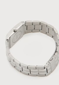 Ασημένιο μπρασελέ με συνδέσμους από μέταλλο και ορθογώνια κάσα ρολογιού που δείχνει την πίσω όψη με χαραγμένο το λογότυπο "BOSS" και πλαϊνό κορώνα.