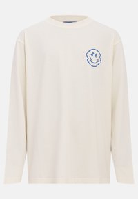 Long-sleeve cream t-shirt in soft fabric, featuring a blue smiley face logo on the left chest. Regular fit with a crew neckline.