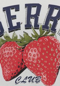 Una tela blanca presenta un diseño de dos grandes fresas rojas con hojas verdes. "BERRY CLUB" está impreso en letras mayúsculas en color marino arriba, acentuado con puntos.