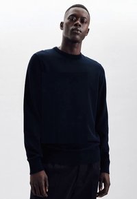 Marineblauwe gebreide trui met lange mouwen, ronde hals en geribbelde manchetten; gladde textuur, minimalistisch ontwerp en een comfortabele pasvorm.