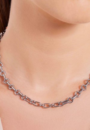 Zilveren metalen kettinghalsband met verbonden ovale en rechthoekige vormen, gepolijste afwerking, rustend op de huid boven het sleutelbeen.