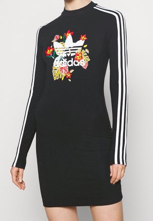 Robe noire Adidas à manches longues avec trois bandes blanches sur les manches et logo trefoil floral imprimé sur la poitrine.