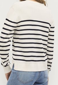 Pull crème avec des rayures navy, manches longues, col rond, fentes sur les côtés et bords côtelés au niveau des manches et de l'ourlet. Texture douce, coupe décontractée.