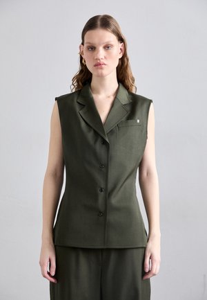 Bezrukavni, prilagođeni prsluk od tamnozelene tkanine s suptilnom teksturom, s izrezanom kragnom, pet dugmadi i malim džepom na prsima.