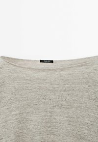 Helles graues Strickoberteil mit weitem Ausschnitt, das eine strukturierte Oberflächenbeschaffenheit und subtile Sprenkel aufweist. Das Etikett trägt die Aufschrift "Massimo Dutti."
