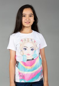 T-shirt bianco in cotone con un design grafico colorato che raffigura una ragazza con trecce e grandi occhi, accentuato da forme geometriche e testo.