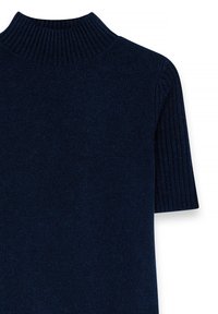 Tumesinine kudumüts, millel on ribakujuline mock-kaelus ja lühikesed varrukad. Sile tekstuur, sisaldades tiheda ja lahtise kudumise mustreid.