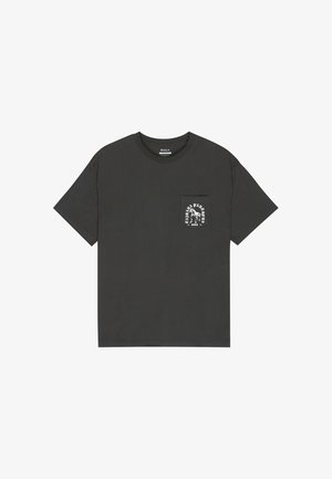 T-shirt nera a maniche corte con collo rotondo e una piccola tasca sul petto sinistro con testo grafico bianco e un'illustrazione.