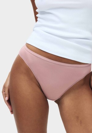 Jasnoróżowe figi wykonane z gładkiego, elastycznego materiału; niski stan z cienką elastyczną gumką i schludnymi krawędziami; minimalne zdobienia.