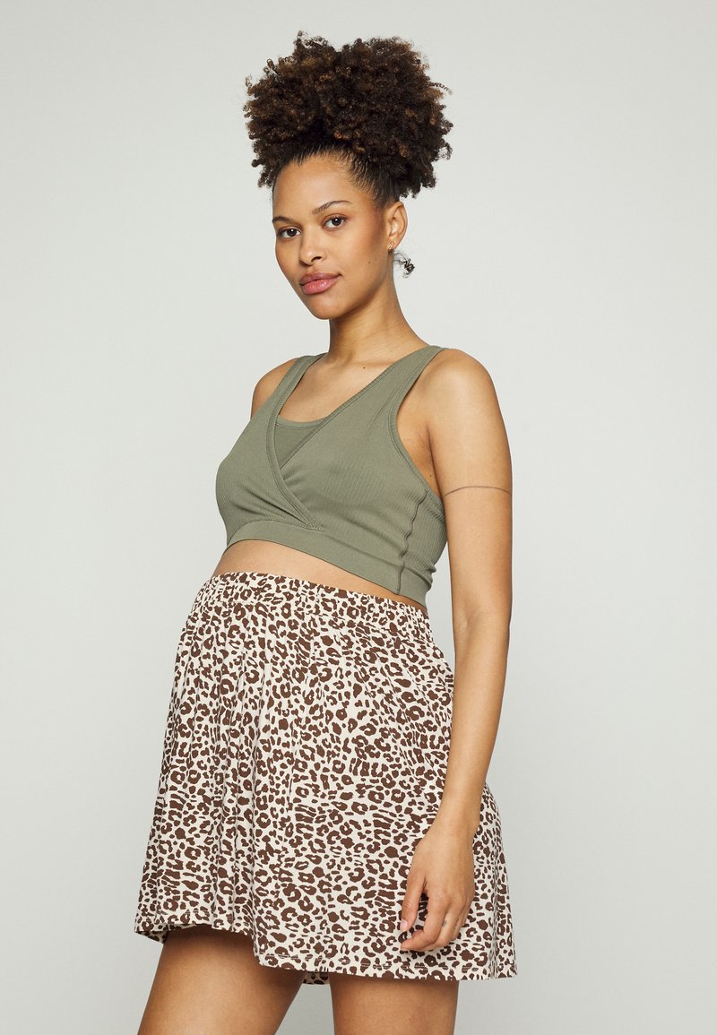 Top de tanque curto verde-oliva com um design drapeado, combinado com uma saia bege com um padrão de estampa de leopardo castanho, de textura suave.