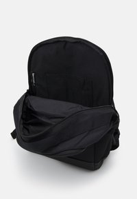 Svart ryggsäck med en dragkedjeöppning, med ett rymligt inre och en extra ficka. Tillverkad av slitstarkt material med en mjuk yta.