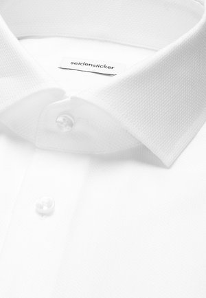 Close-up van een witte overhemdkraag en knopen met een "seidensticker" merklabel aan de binnenkant van de halslijn.