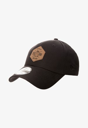 Czarna czapka z daszkiem z brązową sześciokątną łatą z napisem "Buffalo New Era Since 1920" i zakrzywionym rondem z srebrną naklejką.