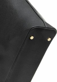 Rogaty czarny skórzany torebka w narożniku z teksturowaną powierzchnią, ozdobiona złotymi ćwiekami i kontrastowym przeszyciem wzdłuż brzegów.