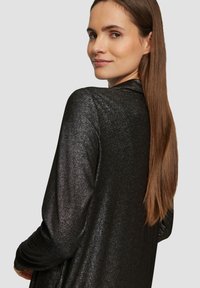 Czarna, połyskująca długosleeve'owa odzież o luźnym kroju, z dekoltem w serek i gładką fakturą, elegancko opadająca na ramionach.