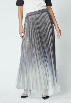 Gonna maxi plissettata in tessuto grigio metallico, effetto ombré che sfuma verso l'orlo traslucido, vita elastica, abbinata a tacchi neri.