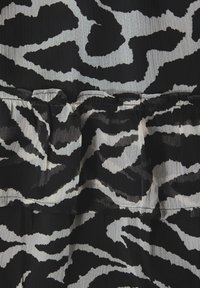 Skaterkjole med sort og hvid zebra mønster, der har en tekstureret stof og lagdelte flæsedetaljer ved kanten.