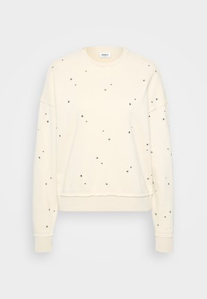 Sweatshirt de couleur crème avec des manches longues, orné de clous métalliques dispersés, poignets côtelés et col rond.