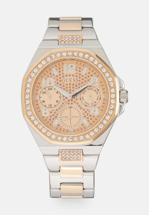 Uz dāmu skatīties ar rozā zelta un sudraba metāla siksniņu. Oktagona formas korpuss ar teksturētu zelta nokrāsas ciparnīcu un dimantiem līdzīgiem akcentiem ap bezel.