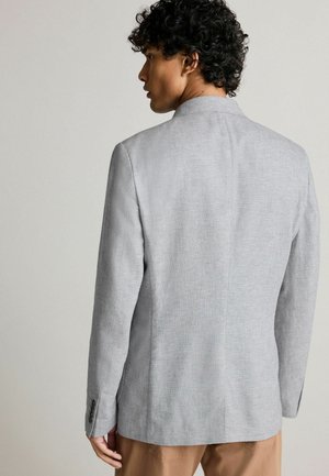 Blazer de lino gris con un diseño moderno, que presenta un cuello estrecho, corte recto y detalles de botones en los puños.