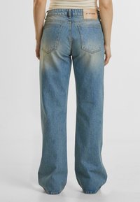 Hoch geschnittene, hellblaue weit geschnittene Jeans aus verblasstem Denim, mit geradem Schnitt und zwei Gesäßtaschen, sowie einem markierten Bund.