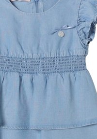 Abito azzurro chiaro realizzato in tessuto morbido, con maniche corte a balze, corpetto arricciato e un bottone decorativo con un nastro decorativo.