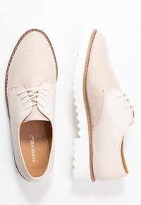 Scarpe casual beige con tomaia in tessuto testurizzato, dettagli in pelle liscia, punta rotonda, chiusura con lacci e suola bianca e imbottita.