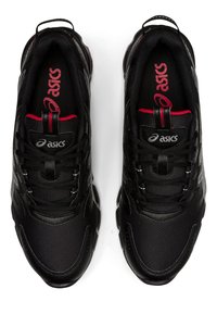 Scarpe da ginnastica nere con tomaia in tessuto a rete, collo imbottito, dettagli rossi e suola in gomma con un motivo a treccia ondulato.