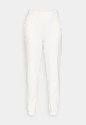 Pantalones de chándal blancos ajustados con cintura y puños elásticos, con bolsillos laterales, expuestos sobre un fondo liso.