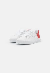 Baskets blanches avec une tige en cuir lisse, accent de talon rouge et semelle en caoutchouc texturé. Présente des œillets ronds et des lacets en textile.